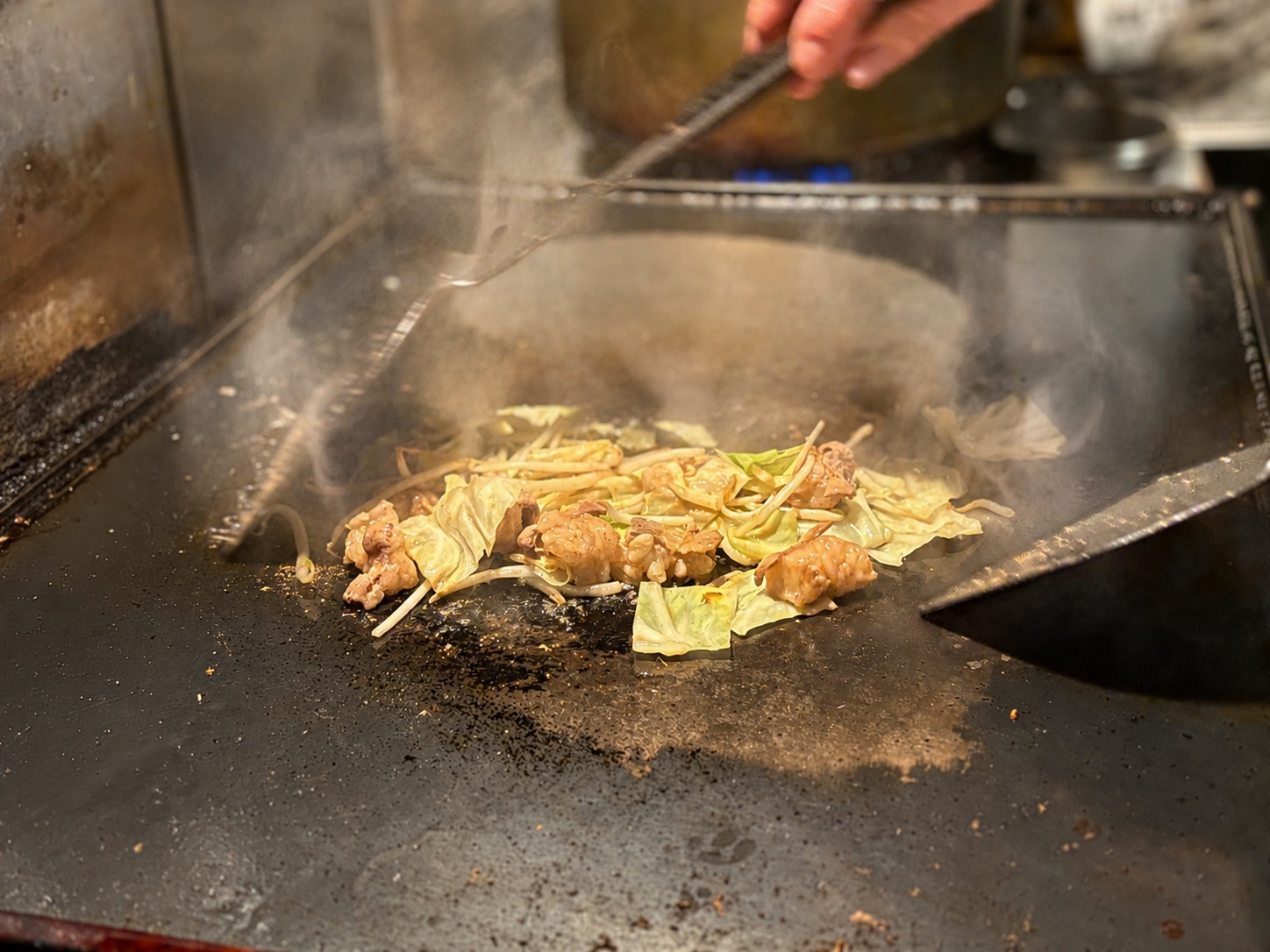湯気の上がる鉄板と調理中の料理